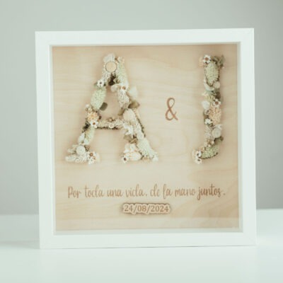 Marco de madera con dos iniciales en flor preservada y frase